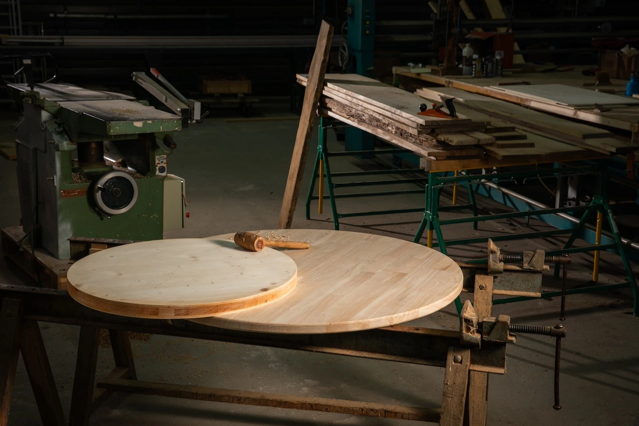 Photo de l'atelier de fabrication des plateaux ronds en bois en Dordogne avec un plateau au premier plan